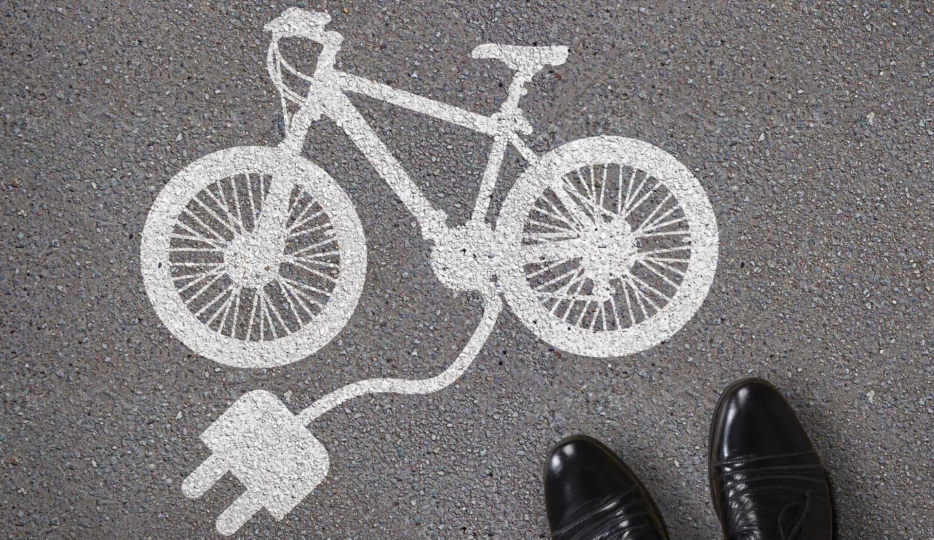 Close-up Of Person’s Feet Standing Next To Painted Electric Bicycle On Asphalt